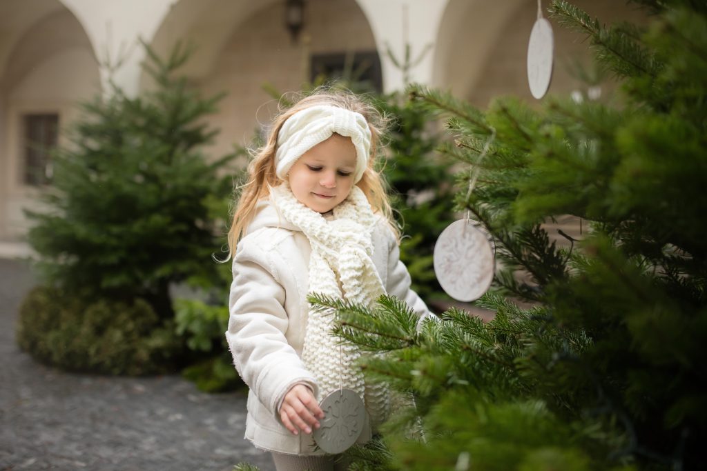 Dievčatko pri vianočných stromčekoch v meste